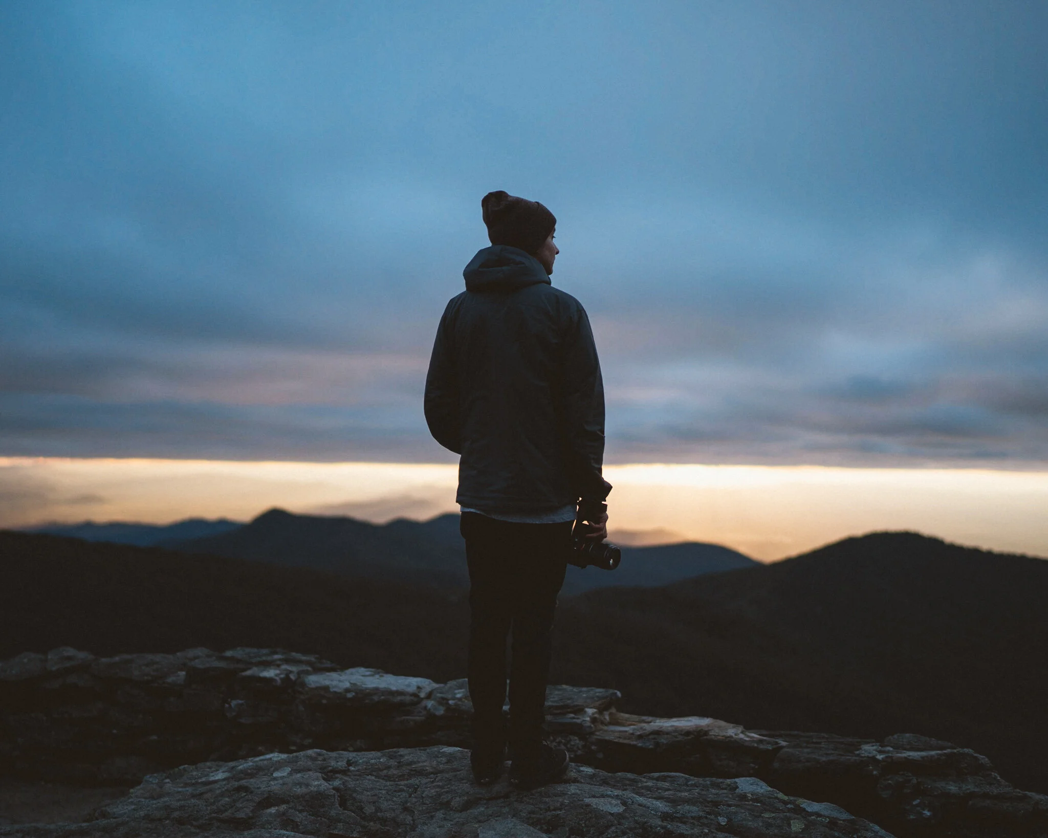 Justin Hardigree standing on a ridge at dusk, camera in hand